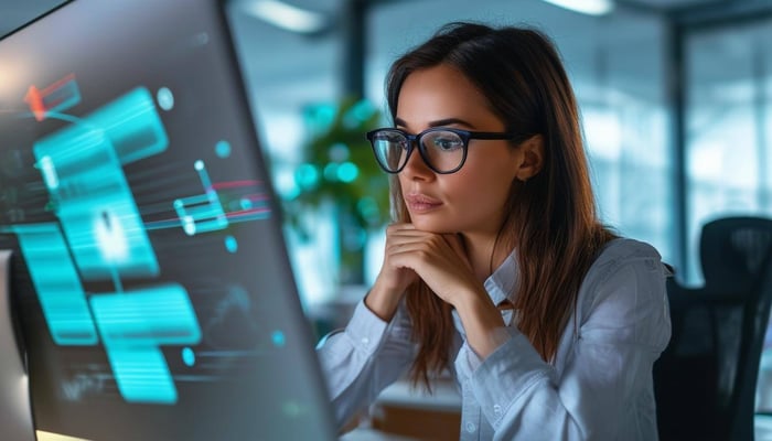 A woman thoughtfully looking at her computer and thinking about the year end and goals for the new year.